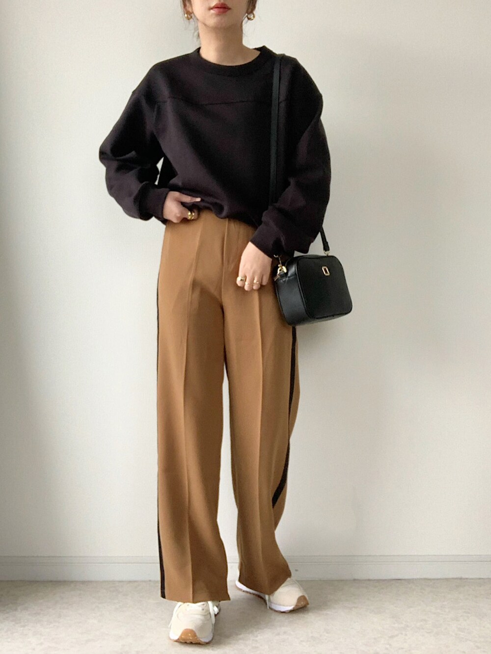 ホワイト系のスニーカー、ブラック系のショルダーバッグ、ホワイト系のTシャツ/カットソーを着用したレディースの秋コーディネートの2枚目の写真