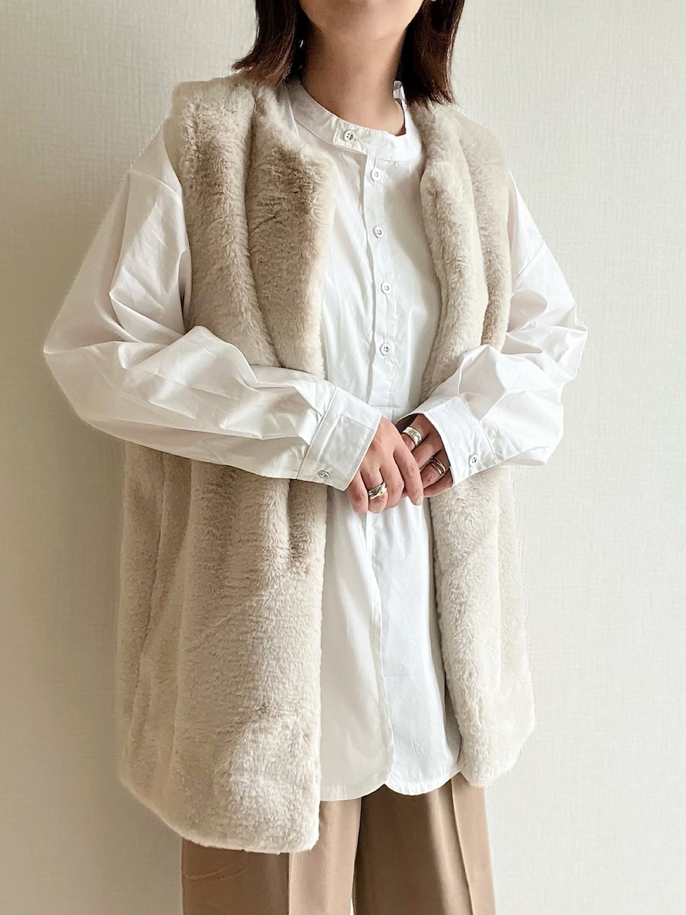 グレー系のベスト、ホワイト系のシャツ/ブラウス、ブラウン系のショルダーバッグを着用したレディースの秋コーディネートの2枚目の写真