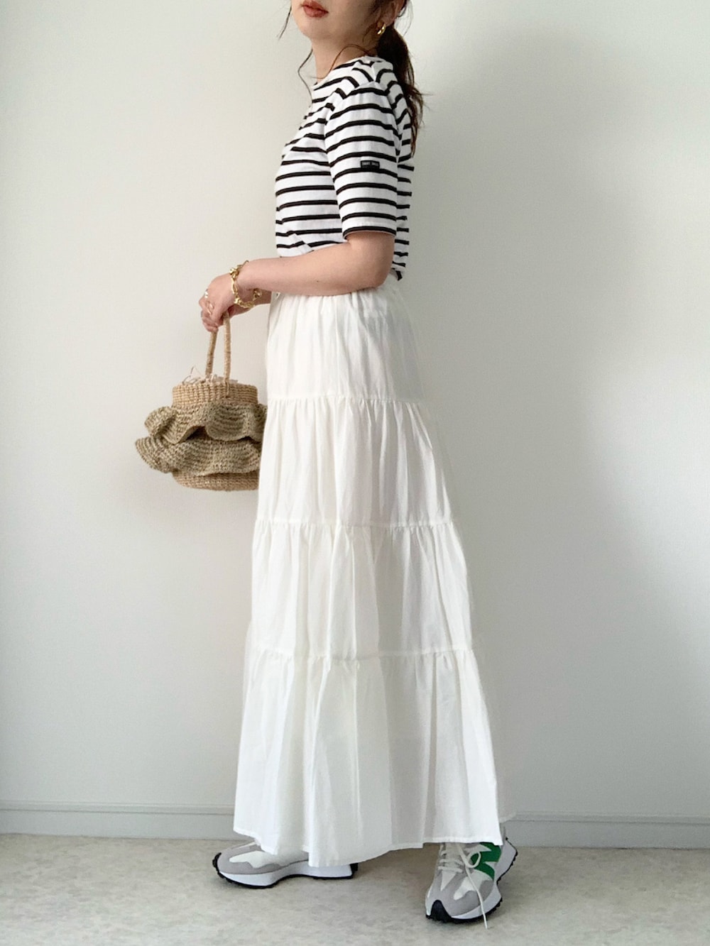 ブラック系のTシャツ/カットソー、ホワイト系のスカート、ブラック系のサンダルを着用したレディースの春コーディネートの2枚目の写真