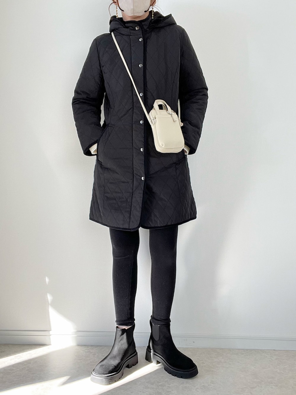 ブラック系のその他アウター、ホワイト系のTシャツ/カットソー、ホワイト系のハンドバッグを着用したレディースの冬コーディネートの2枚目の写真