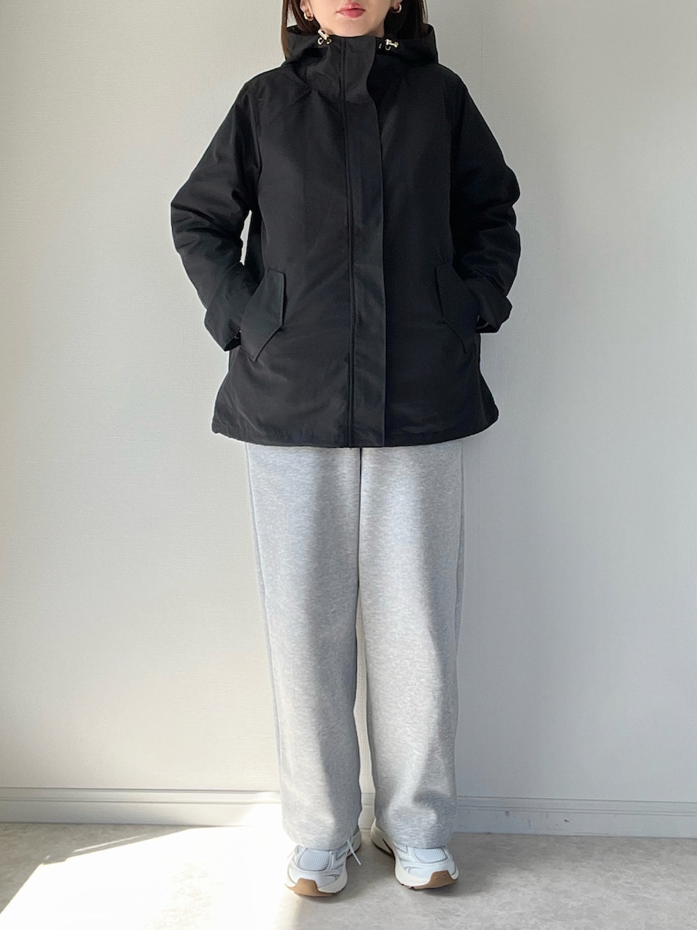 ブラック系のマウンテンパーカー、グレー系のパンツ、ホワイト系のスニーカーを着用したレディースの冬コーディネートの3枚目の写真