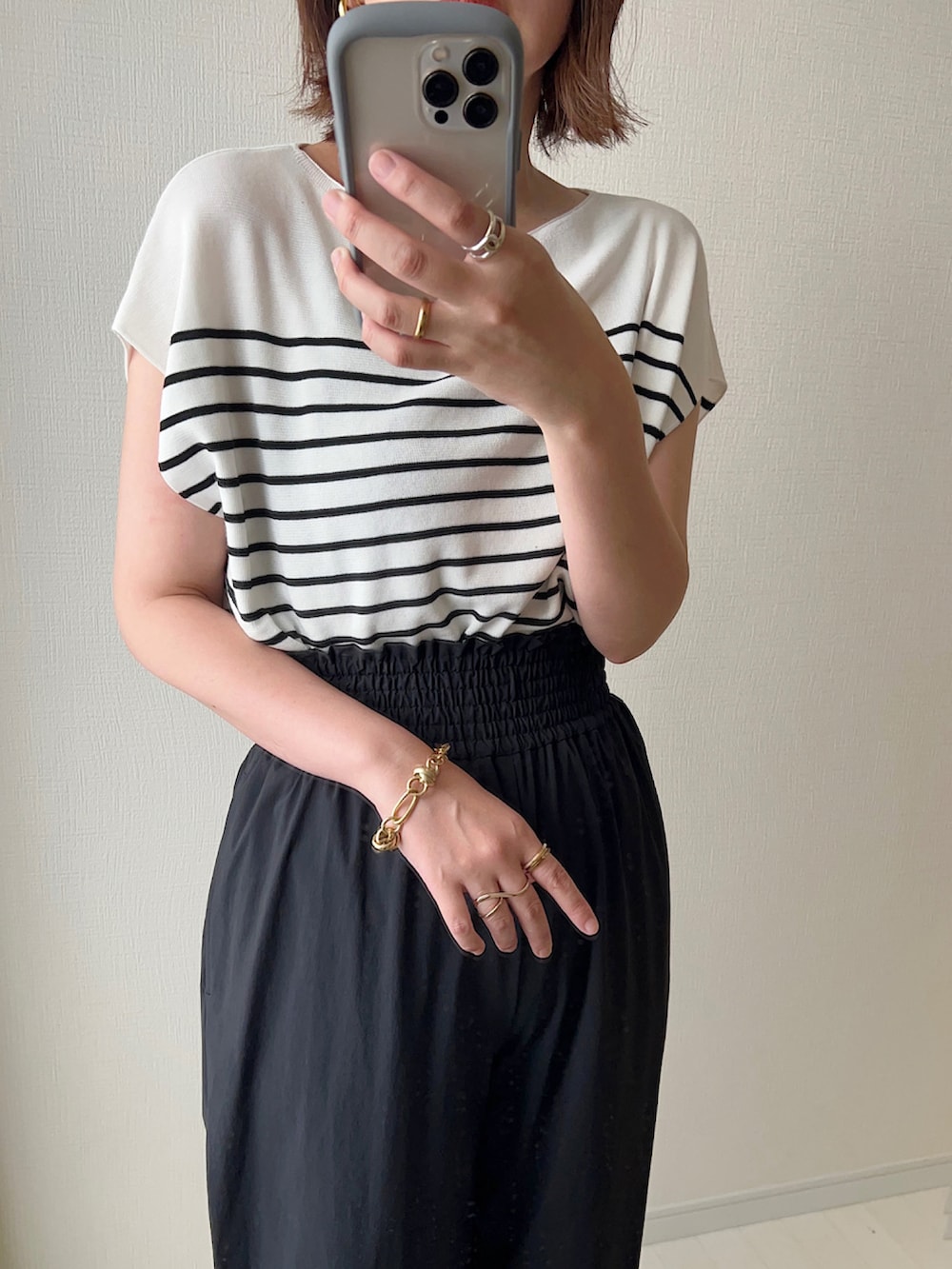 ホワイト系のニット/セーター、ホワイト系のサンダル、ブラック系のショルダーバッグを着用したレディースの夏コーディネートの2枚目の写真