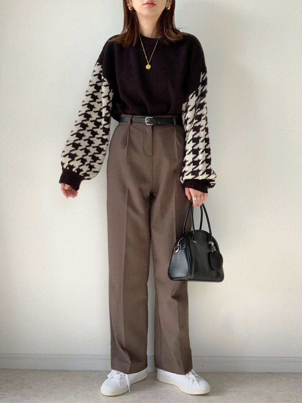 ブラック系のニット/セーター、ブラック系のデニムパンツ、ホワイト系のスニーカーを着用したレディースの冬コーディネートの2枚目の写真