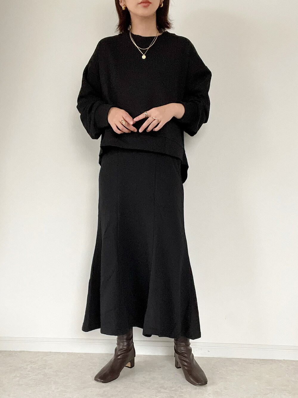 ブラック系のスウェット、ブラック系のスカート、グレー系のベストを着用したレディースの冬コーディネートの2枚目の写真