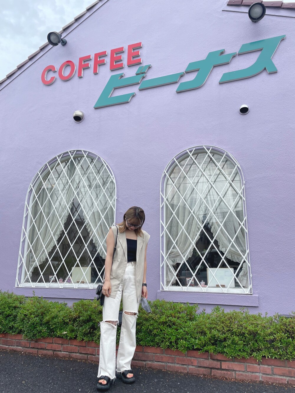 ブラック系のキャミソール、ベージュ系のベスト、ホワイト系のデニムパンツを着用したレディースの夏コーディネートの3枚目の写真