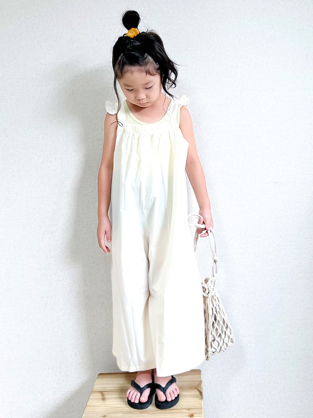 イエロー系のタンクトップ、ホワイト系のつなぎ/オールインワン、ブラック系のサンダルを着用したキッズの夏コーディネートの3枚目の写真