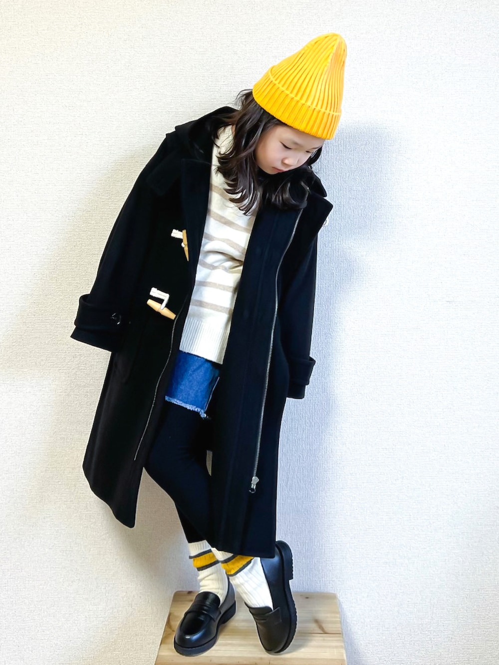 ブラック系のダッフルコート、ホワイト系のニット/セーター、ブルー系のデニムパンツを着用したキッズの秋コーディネートの3枚目の写真