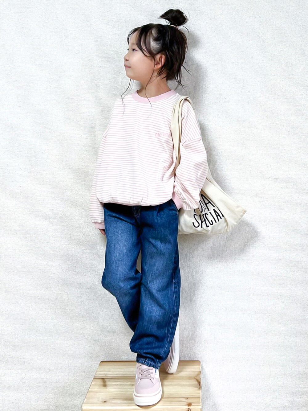 ピンク系のスウェット、ブルー系のデニムパンツ、ピンク系のスニーカーを着用したキッズの秋コーディネートの3枚目の写真