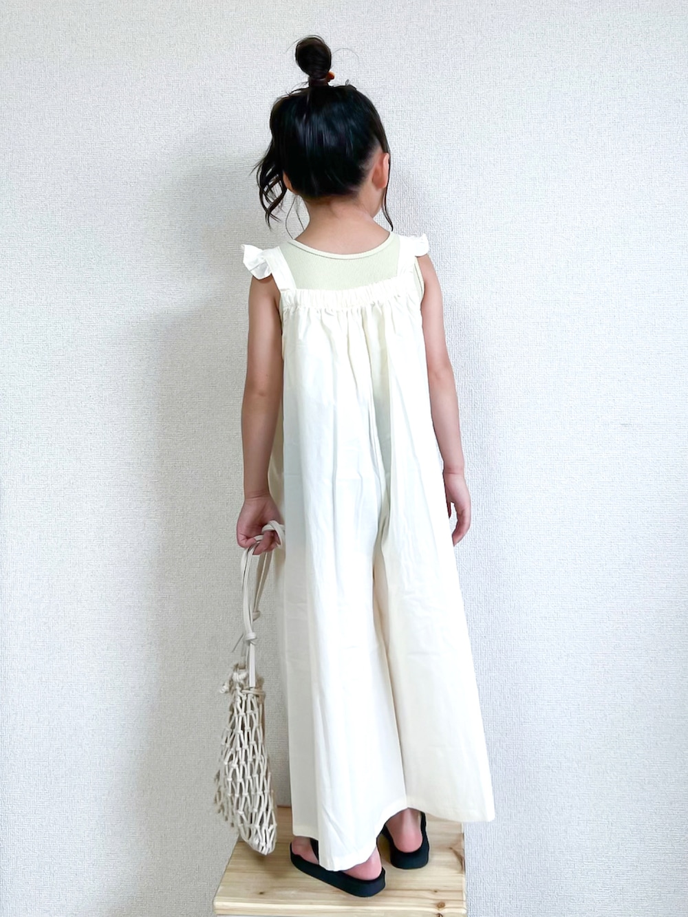 イエロー系のタンクトップ、ホワイト系のつなぎ/オールインワン、ブラック系のサンダルを着用したキッズの夏コーディネートの2枚目の写真