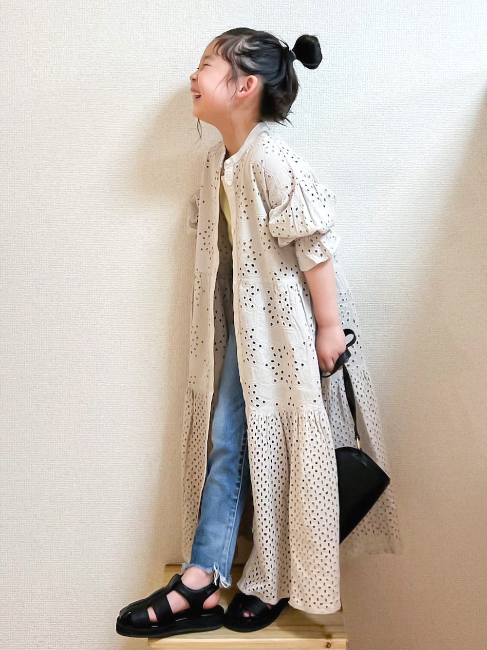 グレー系のワンピース、イエロー系のタンクトップ、ブルー系のデニムパンツを着用したキッズの春コーディネートの3枚目の写真