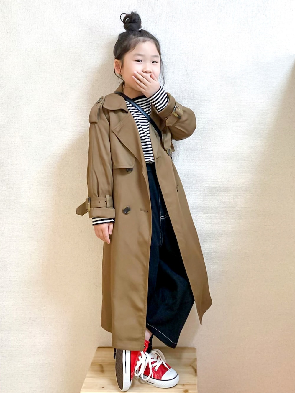 イエロー系のトレンチコート、ブラック系のTシャツ/カットソー、ブラック系のその他パンツを着用したキッズの春コーディネートの3枚目の写真