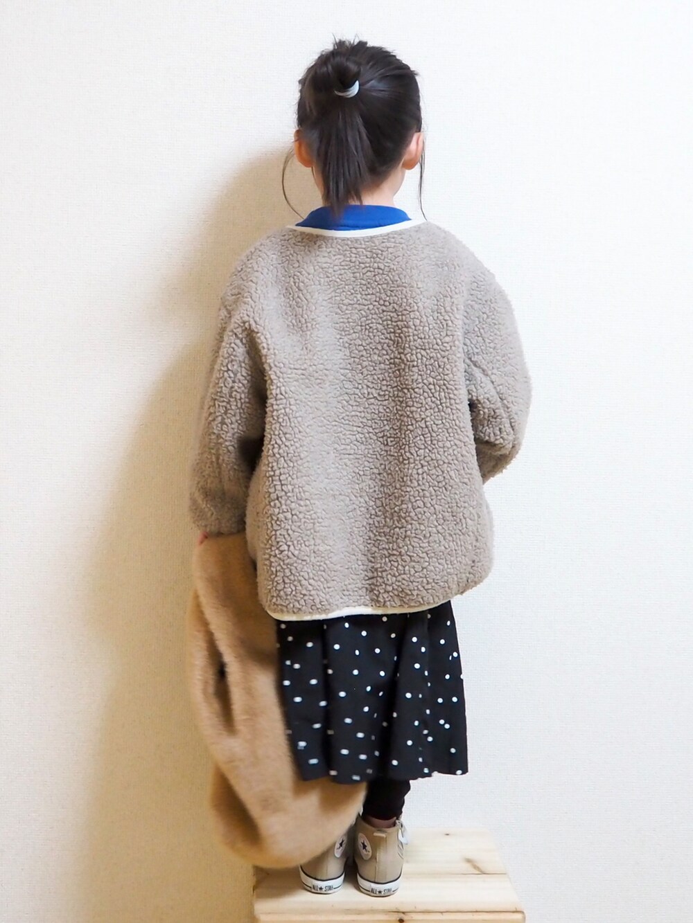 ブルー系のスウェット、ベージュ系のブルゾン、ブラック系のスカートを着用したキッズの冬コーディネートの2枚目の写真