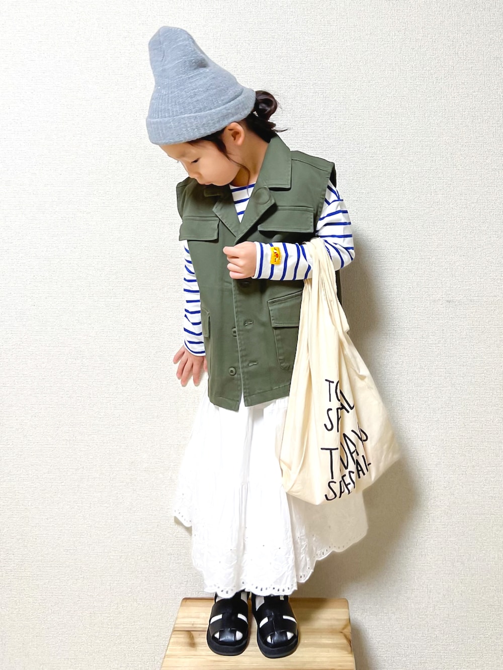 グリーン系のベスト、ホワイト系のTシャツ/カットソー、ホワイト系のスカートを着用したキッズの秋コーディネートの3枚目の写真