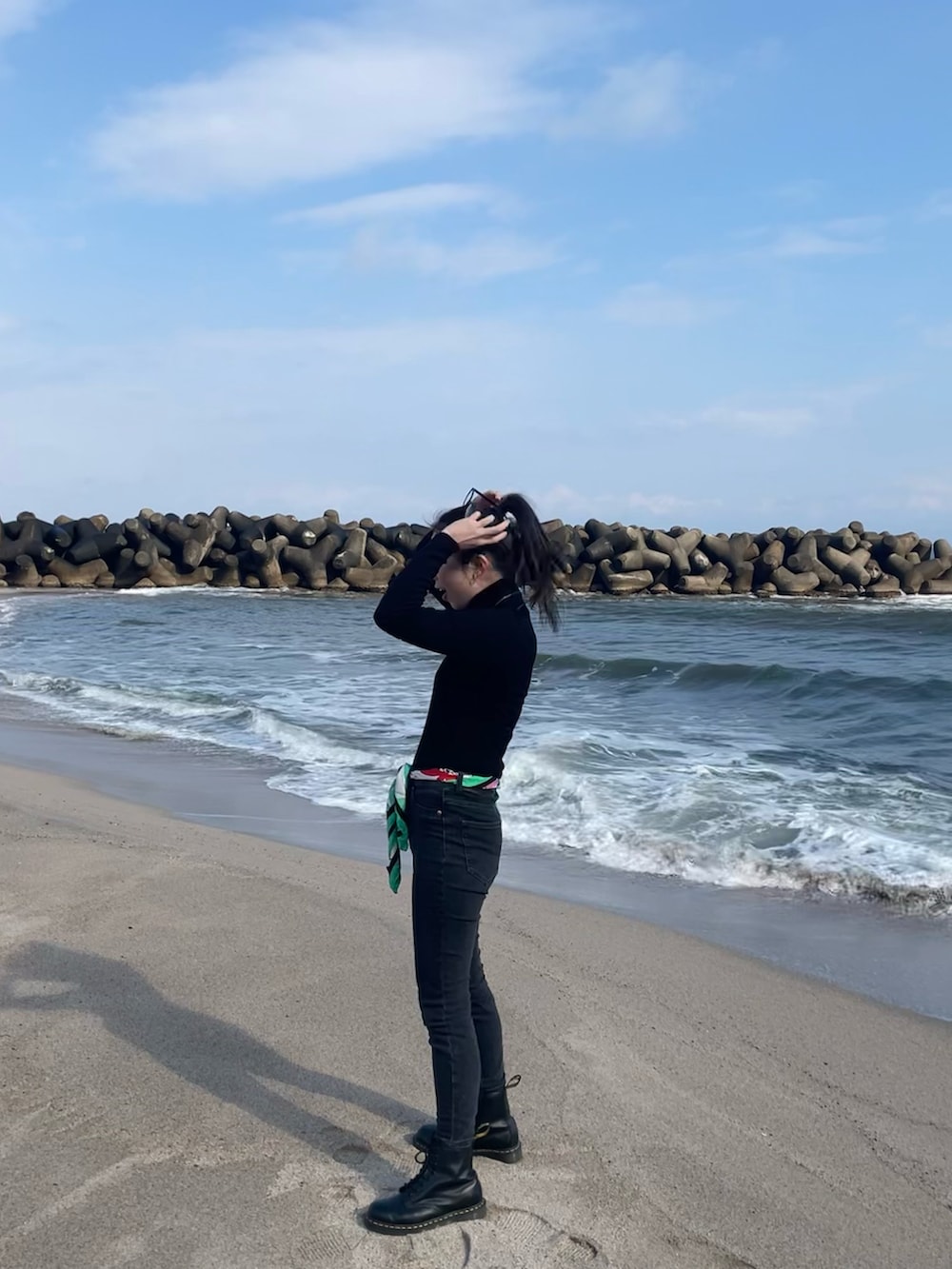 ブラック系のニット/セーター、ベージュ系のジャケット/アウター、ブラック系のブーツを着用したレディースの冬コーディネートの2枚目の写真