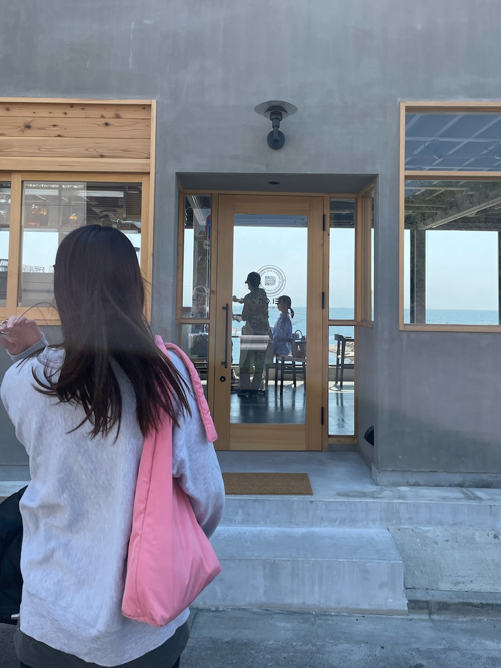 グレー系のスウェット、ブルー系のデニムパンツ、ブラック系のスニーカーを着用したレディースの夏コーディネートの2枚目の写真