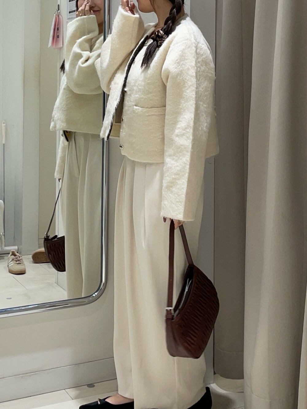 ホワイト系のスラックス、ブラック系のパンプス、ホワイト系のブルゾンを着用したレディースの秋コーディネートの2枚目の写真