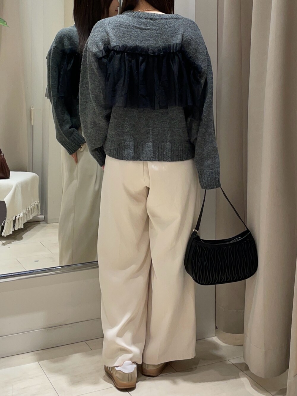 グレー系のニット/セーター、ホワイト系のスラックス、ブラック系のベルトを着用したレディースの秋コーディネートの2枚目の写真