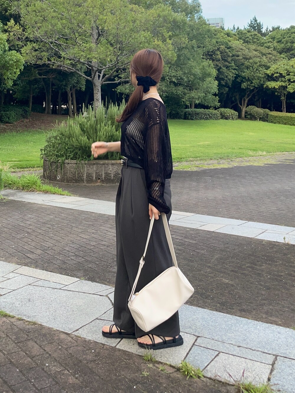 ブラック系のニット/セーター、グレー系のスラックス、ホワイト系のトートバッグを着用したレディースの夏コーディネートの2枚目の写真
