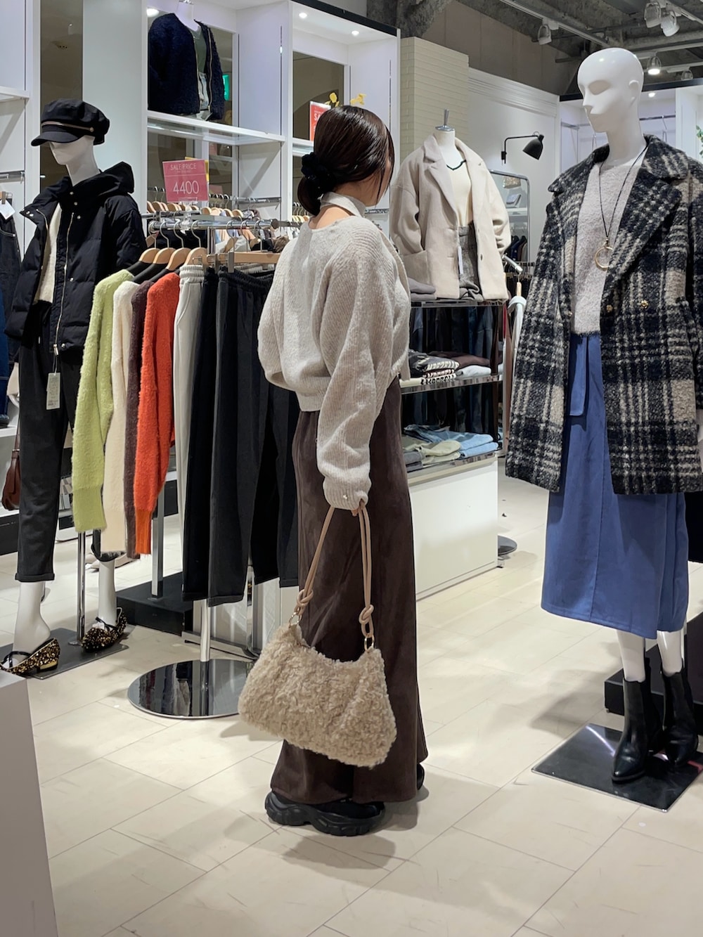 ベージュ系のニット/セーター、ブラウン系のスカート、ベージュ系のトートバッグを着用したレディースの秋コーディネートの2枚目の写真