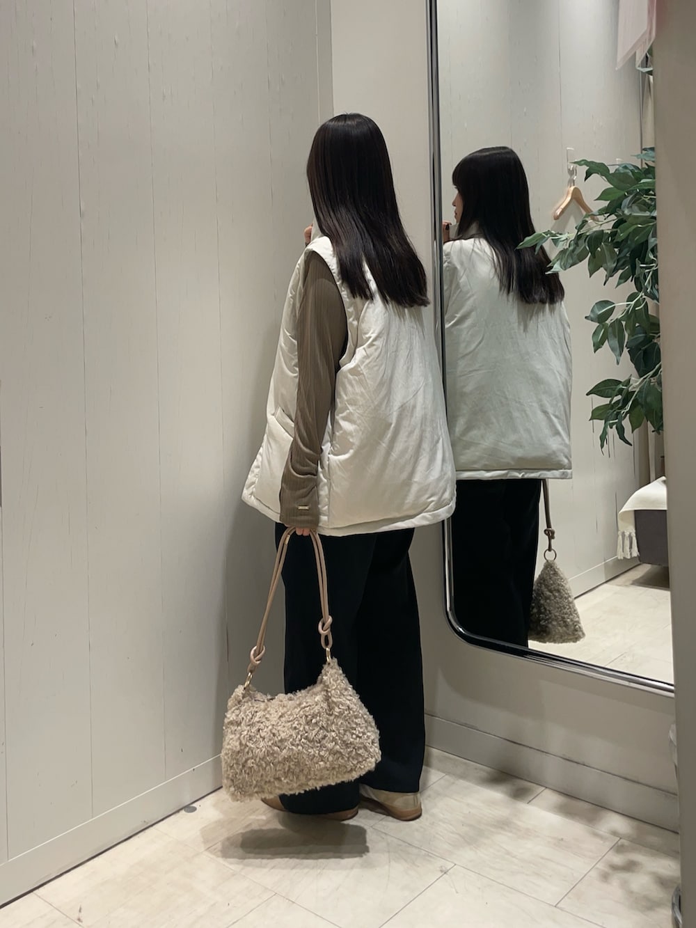 ホワイト系のブルゾン、ベージュ系のTシャツ/カットソー、ブラック系のスラックスを着用したレディースの冬コーディネートの2枚目の写真