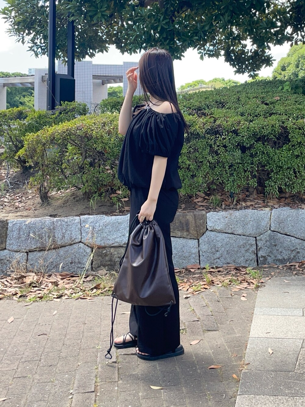 ブラック系のつなぎ/オールインワン、ブラウン系のバックパック/リュックを着用したレディースの夏コーディネートの2枚目の写真