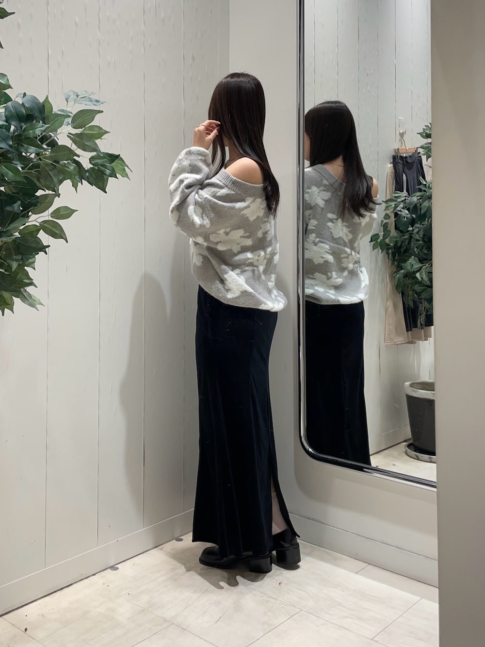 グレー系のニット/セーター、ブラック系のスカート、ブラック系のブーツを着用したレディースの秋コーディネートの2枚目の写真