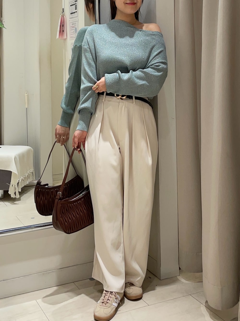 グリーン系のニット/セーター、ホワイト系のスラックス、ブラック系のベルトを着用したレディースの秋コーディネートの4枚目の写真