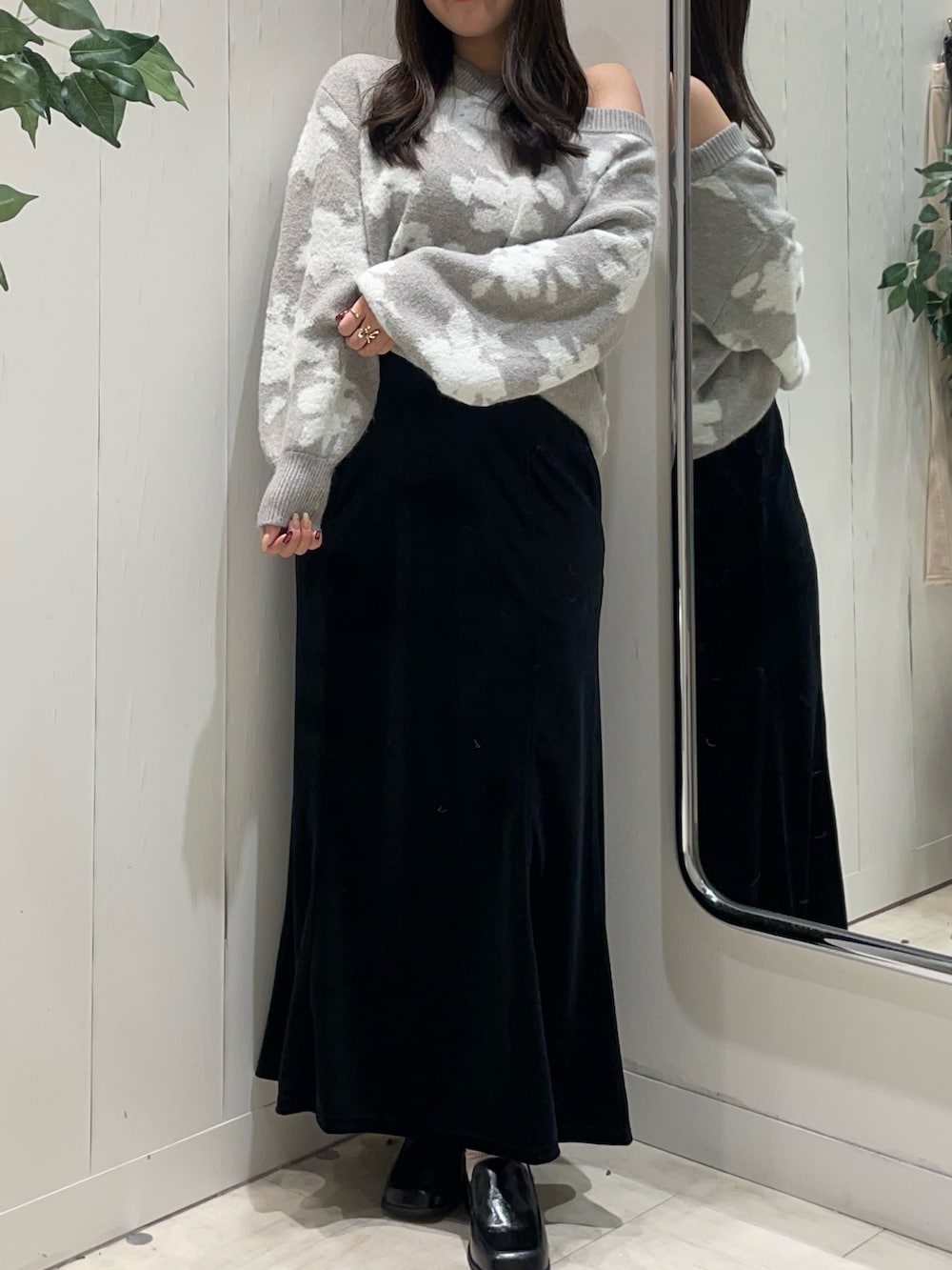 グレー系のニット/セーター、ブラック系のスカート、ブラック系のブーツを着用したレディースの秋コーディネートの4枚目の写真