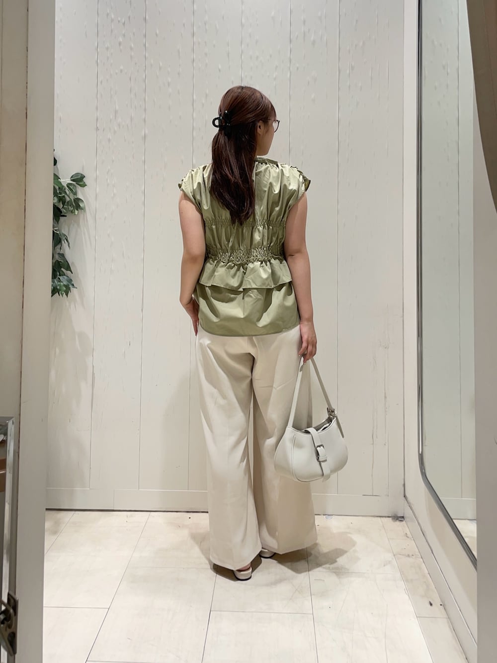 グリーン系のシャツ/ブラウス、ホワイト系のスラックス、ホワイト系のサンダルを着用したレディースの夏コーディネートの2枚目の写真