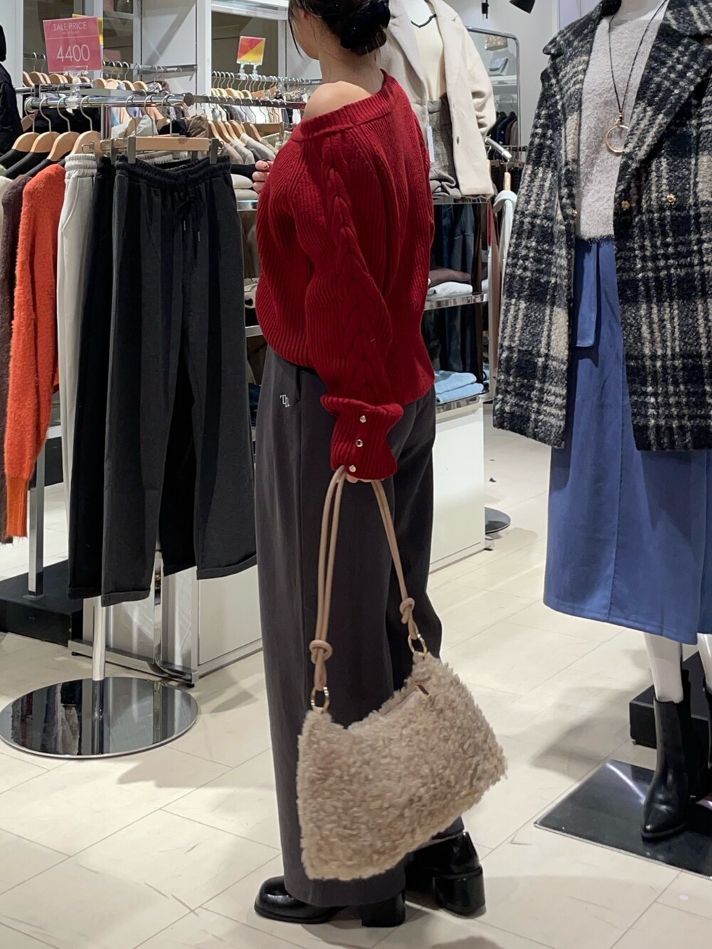 レッド系のニット/セーター、グレー系のその他パンツ、ブラック系のブーツを着用したレディースの秋コーディネートの2枚目の写真