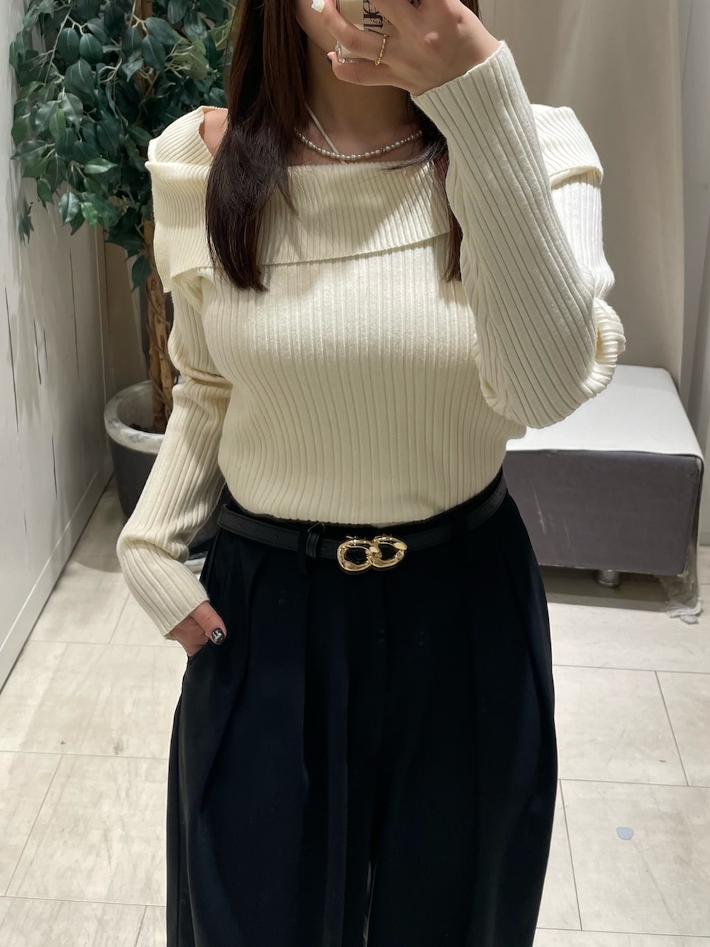 ホワイト系のニット/セーター、ブラック系のスラックス、ブラック系のベルトを着用したレディースの冬コーディネートの2枚目の写真