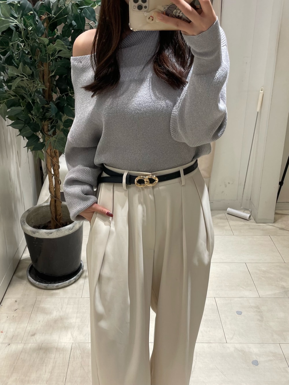 グレー系のニット/セーター、ホワイト系のスラックス、ブラック系のベルトを着用したレディースの秋コーディネートの4枚目の写真