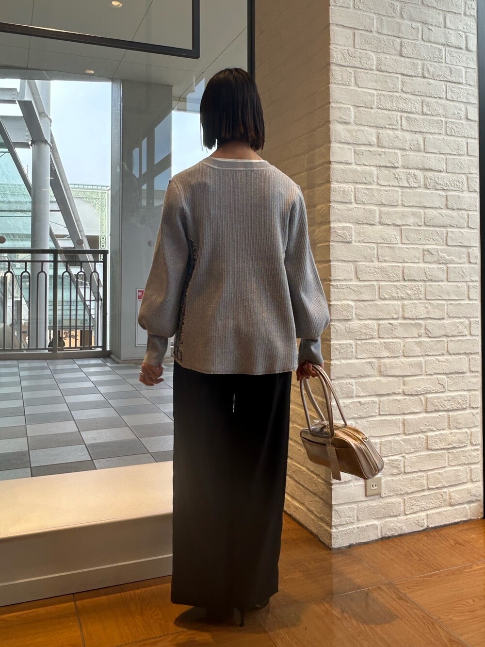 グレー系のニット/セーター、ブラック系のその他パンツ、ホワイト系のボストンバッグを着用したレディースの冬コーディネートの2枚目の写真