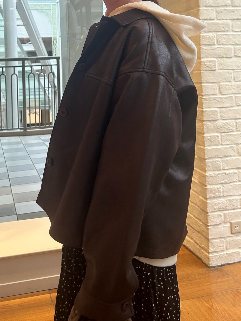 ブラック系のスカート、ブラウン系のブルゾン、ホワイト系のニット/セーターを着用したレディースの秋コーディネートの5枚目の写真