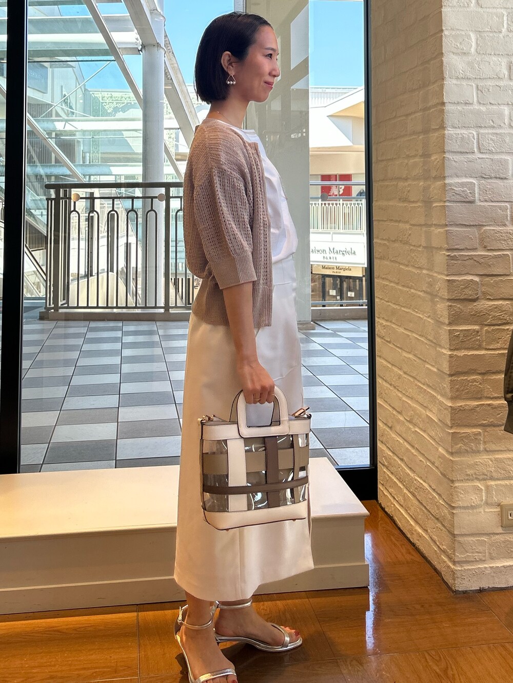 ホワイト系のスカート、ホワイト系のTシャツ/カットソー、ベージュ系のニット/セーターを着用したレディースの春コーディネートの3枚目の写真