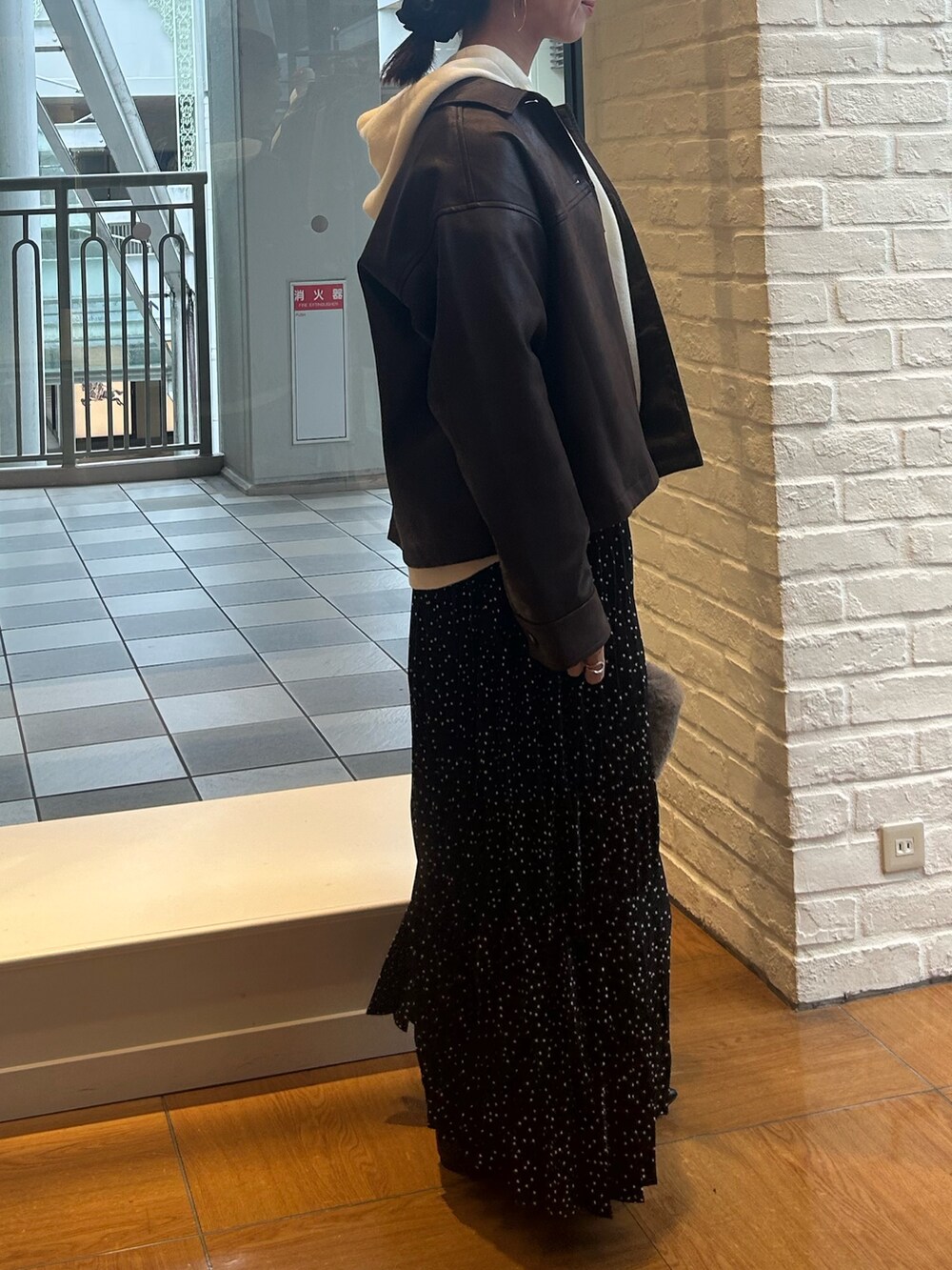 ブラック系のスカート、ブラウン系のブルゾン、ホワイト系のニット/セーターを着用したレディースの秋コーディネートの2枚目の写真