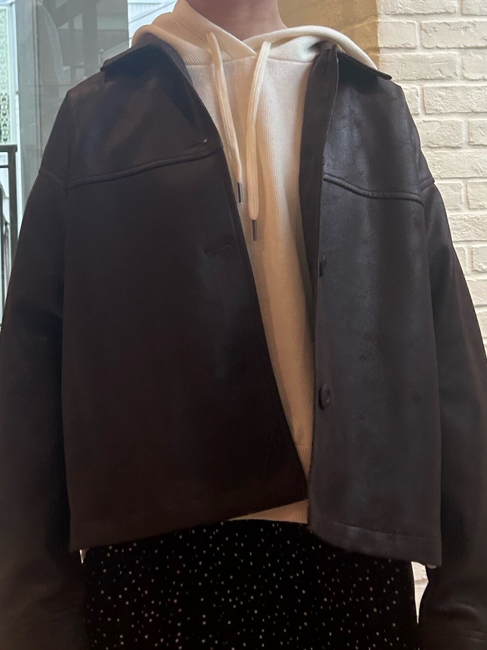 ブラック系のスカート、ブラウン系のブルゾン、ホワイト系のニット/セーターを着用したレディースの秋コーディネートの4枚目の写真