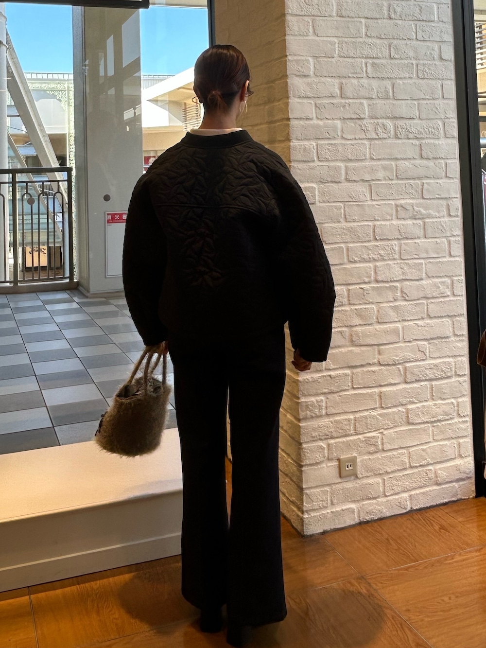 ブラック系のブルゾン、ブルー系のデニムパンツ、ホワイト系のカーディガン/ボレロを着用したレディースの秋コーディネートの3枚目の写真