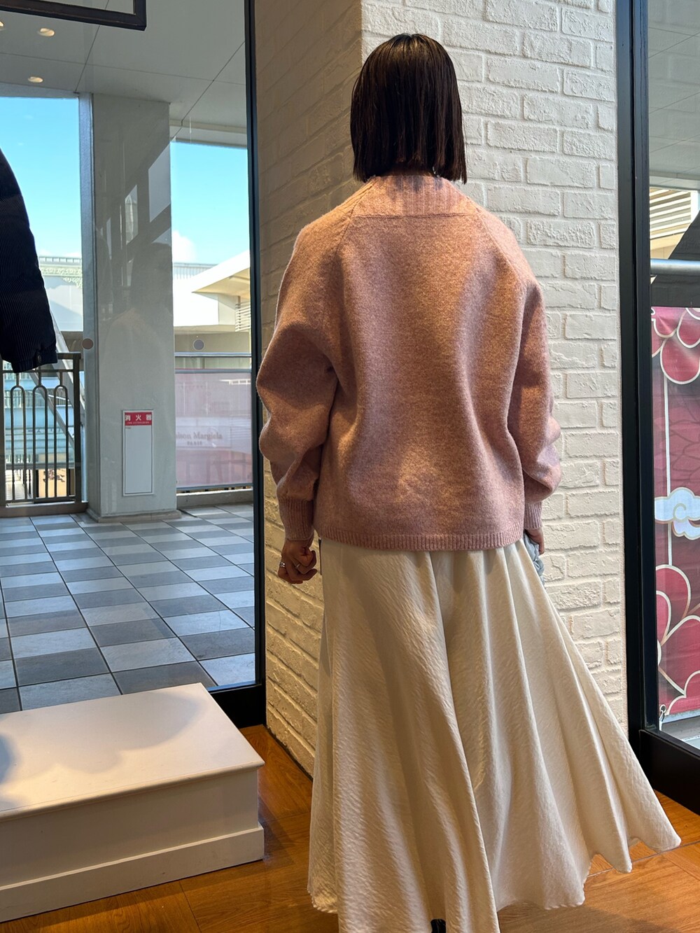 ホワイト系のスカート、オレンジ系のニット/セーターを着用したレディースの冬コーディネートの3枚目の写真
