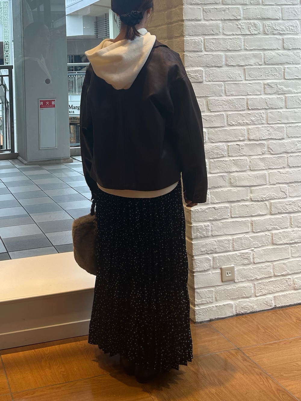 ブラック系のスカート、ブラウン系のブルゾン、ホワイト系のニット/セーターを着用したレディースの秋コーディネートの3枚目の写真