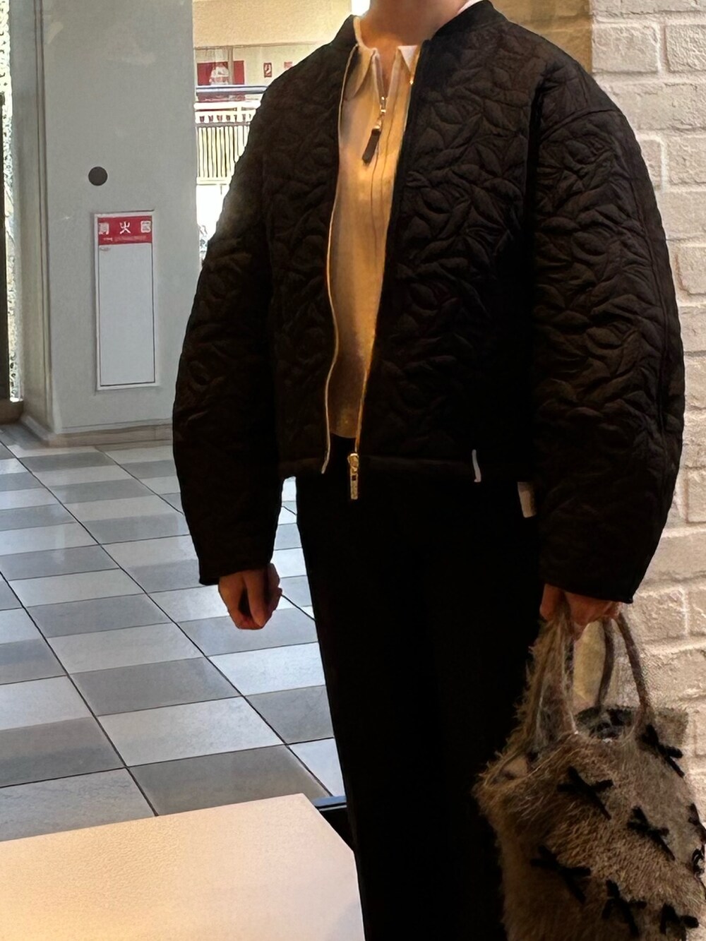 ブラック系のブルゾン、ブルー系のデニムパンツ、ホワイト系のカーディガン/ボレロを着用したレディースの秋コーディネートの4枚目の写真