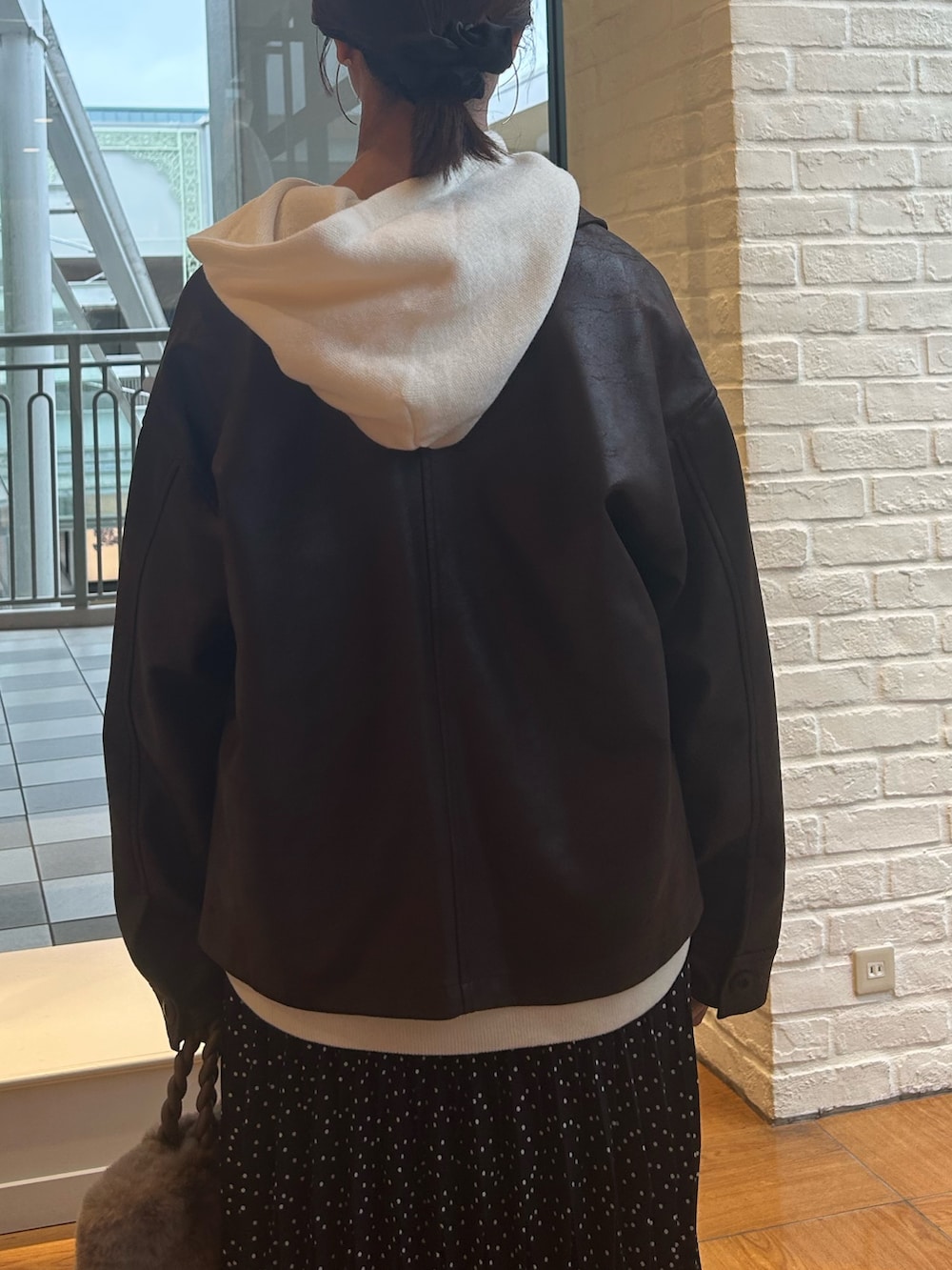 ブラック系のスカート、ブラウン系のブルゾン、ホワイト系のニット/セーターを着用したレディースの秋コーディネートの6枚目の写真