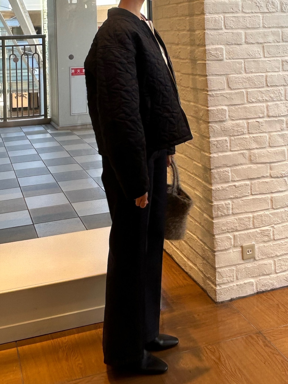 ブラック系のブルゾン、ブルー系のデニムパンツ、ホワイト系のカーディガン/ボレロを着用したレディースの秋コーディネートの2枚目の写真