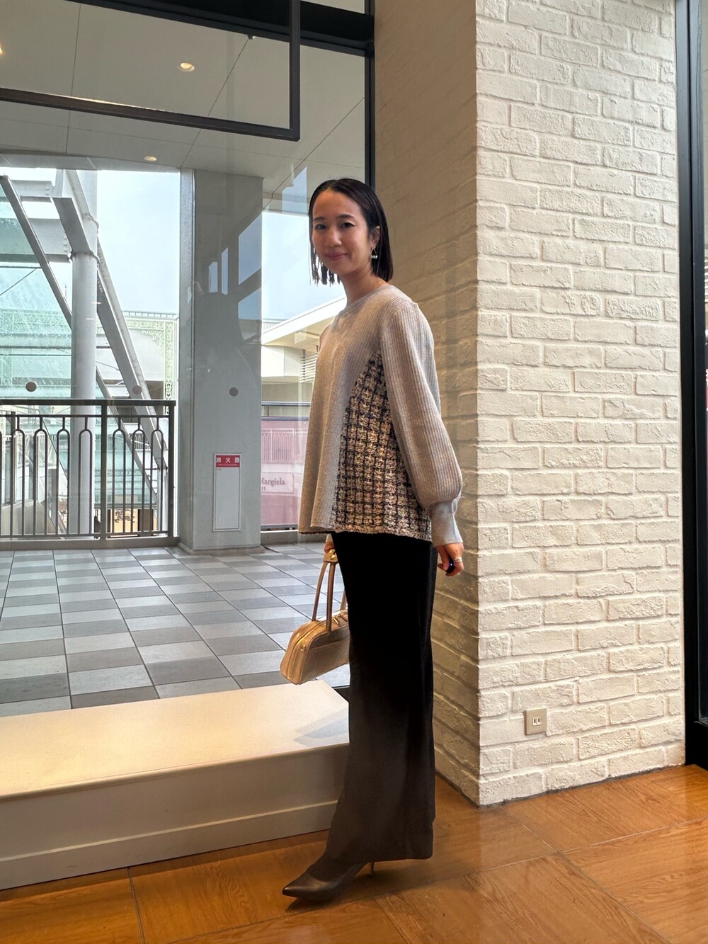 グレー系のニット/セーター、ブラック系のその他パンツ、ホワイト系のボストンバッグを着用したレディースの冬コーディネートの3枚目の写真