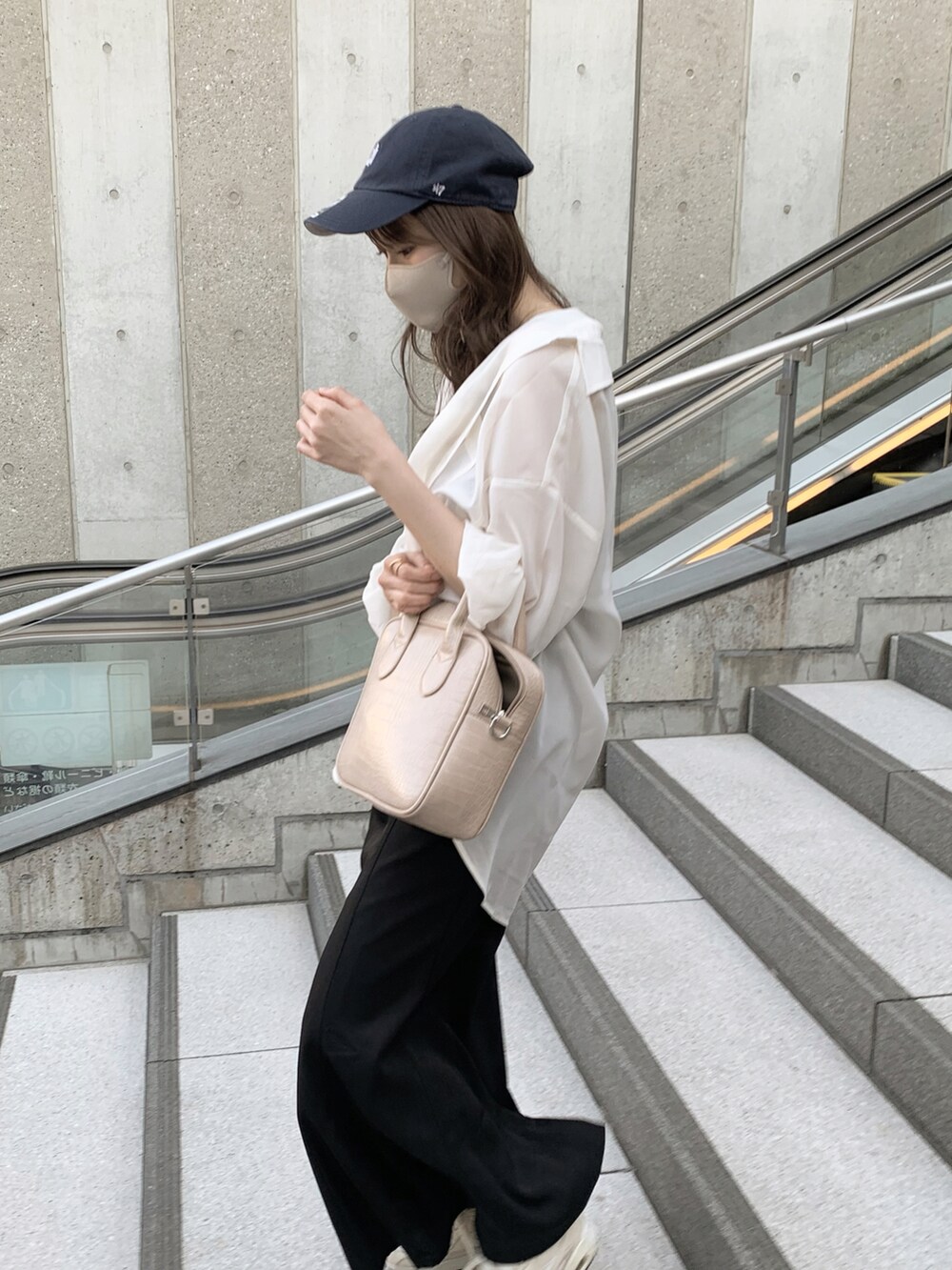 ブラック系のワンピース、ベージュ系のスニーカー、ホワイト系のシャツ/ブラウスを着用したレディースの春コーディネートの2枚目の写真