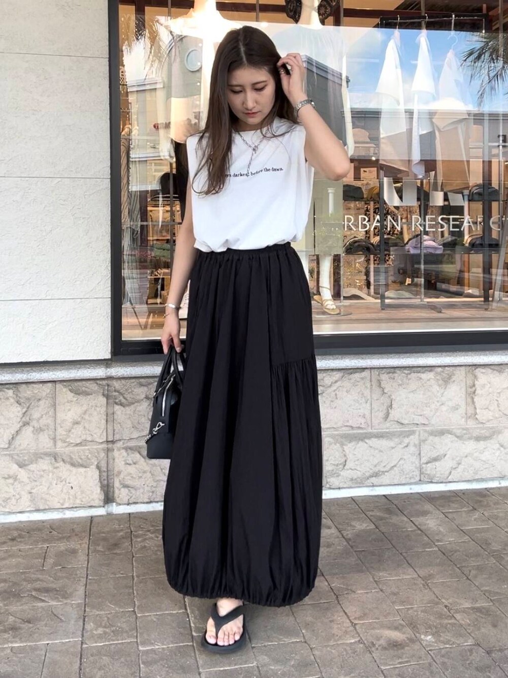 ブラック系のボストンバッグ、ホワイト系のTシャツ/カットソー、ブラック系のスカートを着用したレディースの夏コーディネートの2枚目の写真
