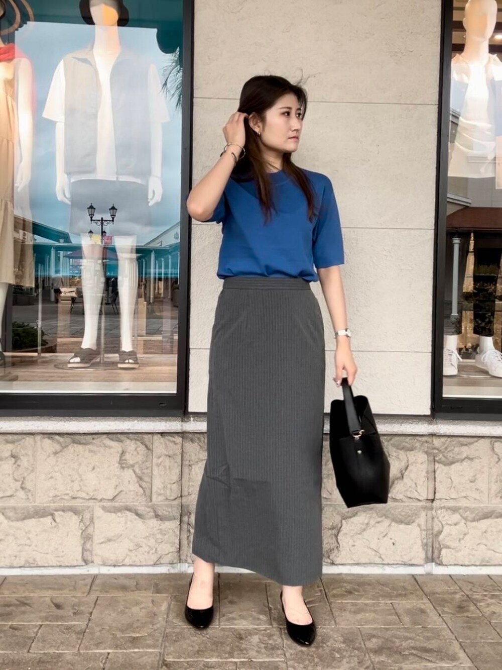 ブルー系のニット/セーター、グレー系のスカートを着用したレディースの秋コーディネートの2枚目の写真