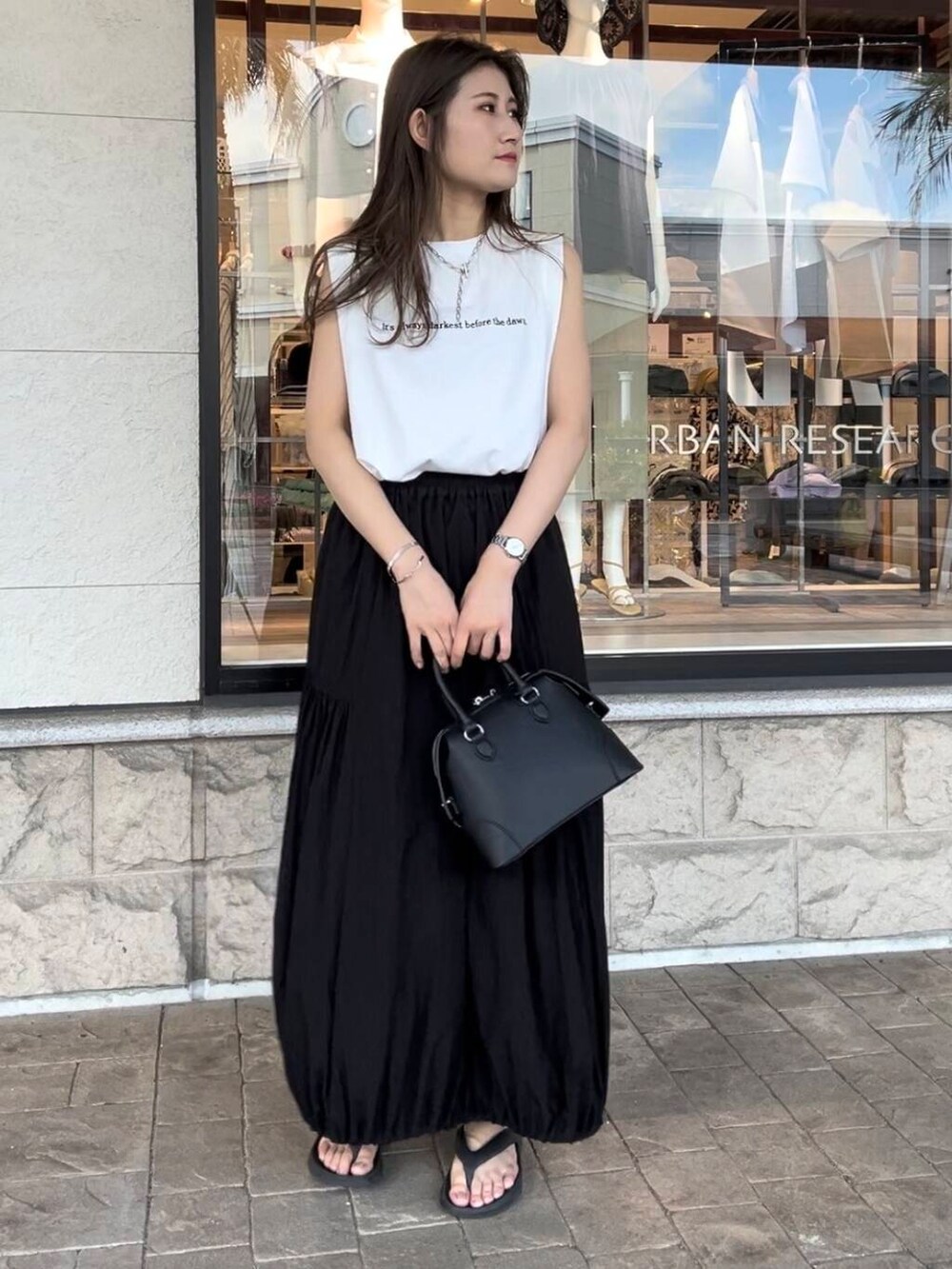 ブラック系のボストンバッグ、ホワイト系のTシャツ/カットソー、ブラック系のスカートを着用したレディースの夏コーディネートの3枚目の写真