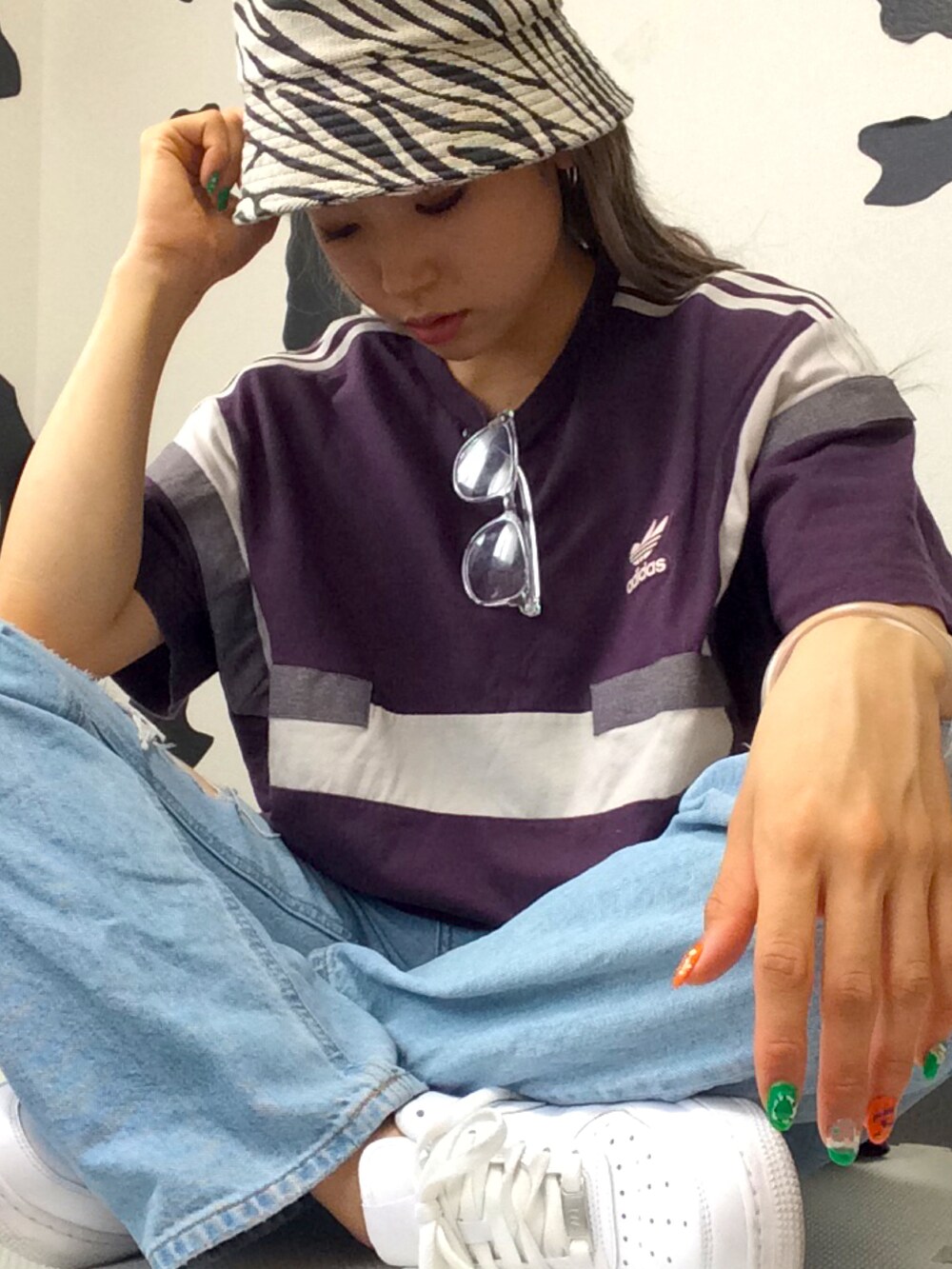 パープル系のTシャツ/カットソー、ホワイト系のクラッチバッグ、ブルー系のデニムパンツを着用したレディースの春コーディネートの2枚目の写真