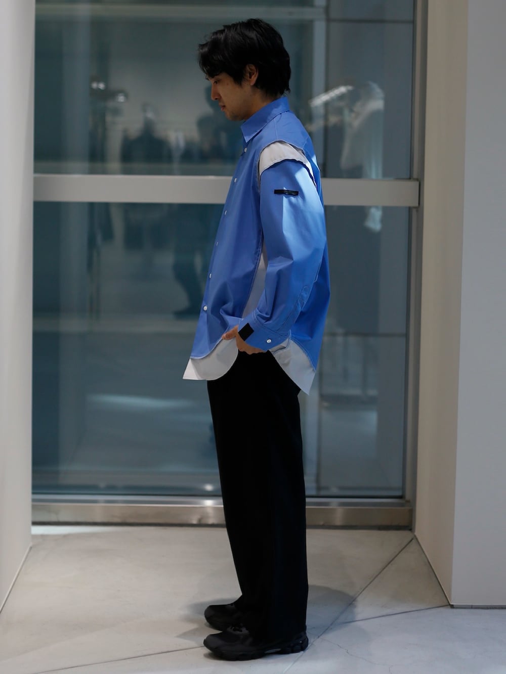 ブルー系のシャツ/ブラウス、ブラック系のスラックス、ブラック系のスニーカーを着用したメンズの春コーディネートの2枚目の写真